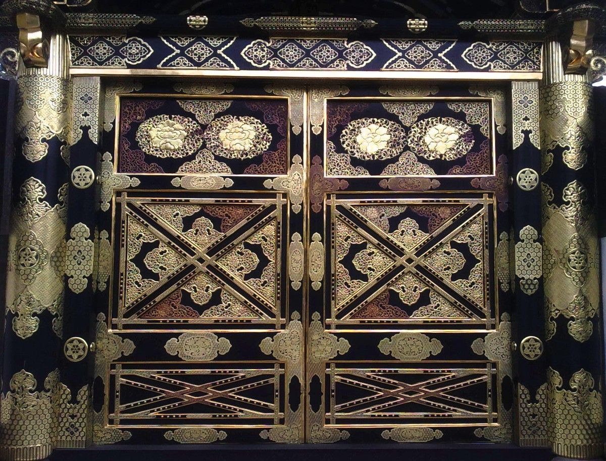 huge double wooden door adorned in intricate brass cutout decorations