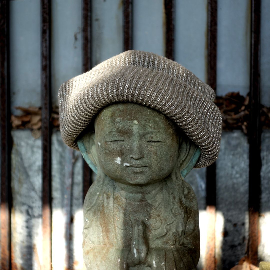 small Buddhist stone figure with a winter beanie