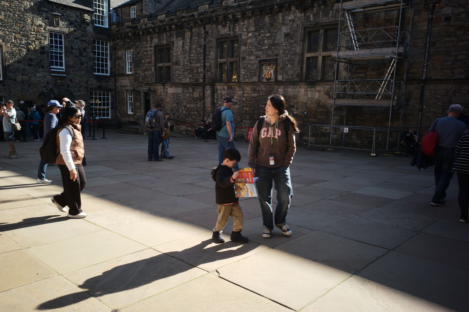 A boy and a lady stand in the middle of the crown square. The boy is holding a child’s guide to Edinburgh castle