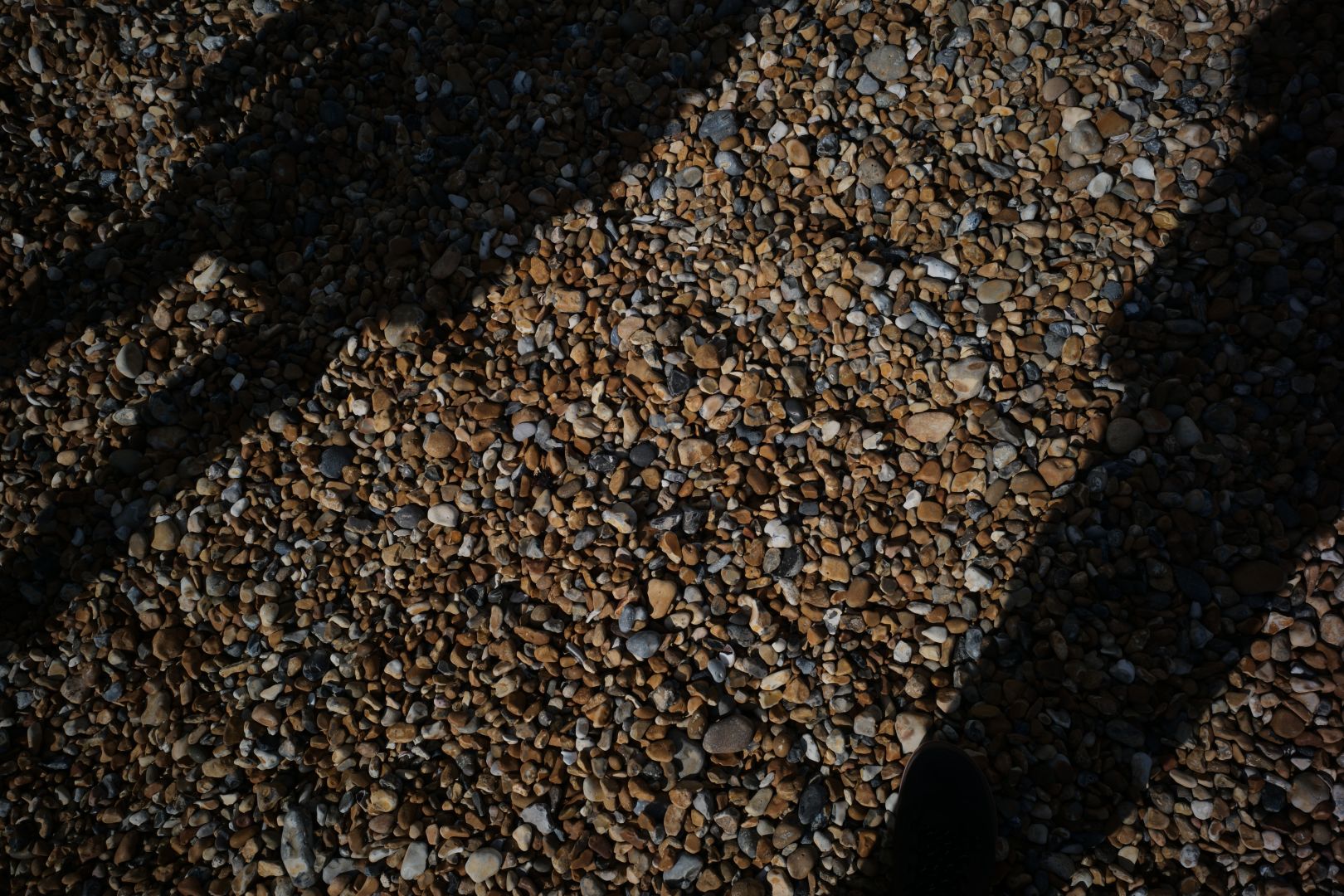 Shadows cast on pebbled beach