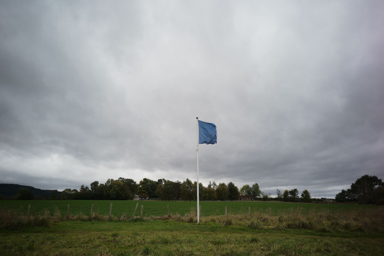 Blue flag flying above a green field. This marks where the highland clans awaited the start of battle. This flag I believe, would have been where the Fraser clan was waiting.