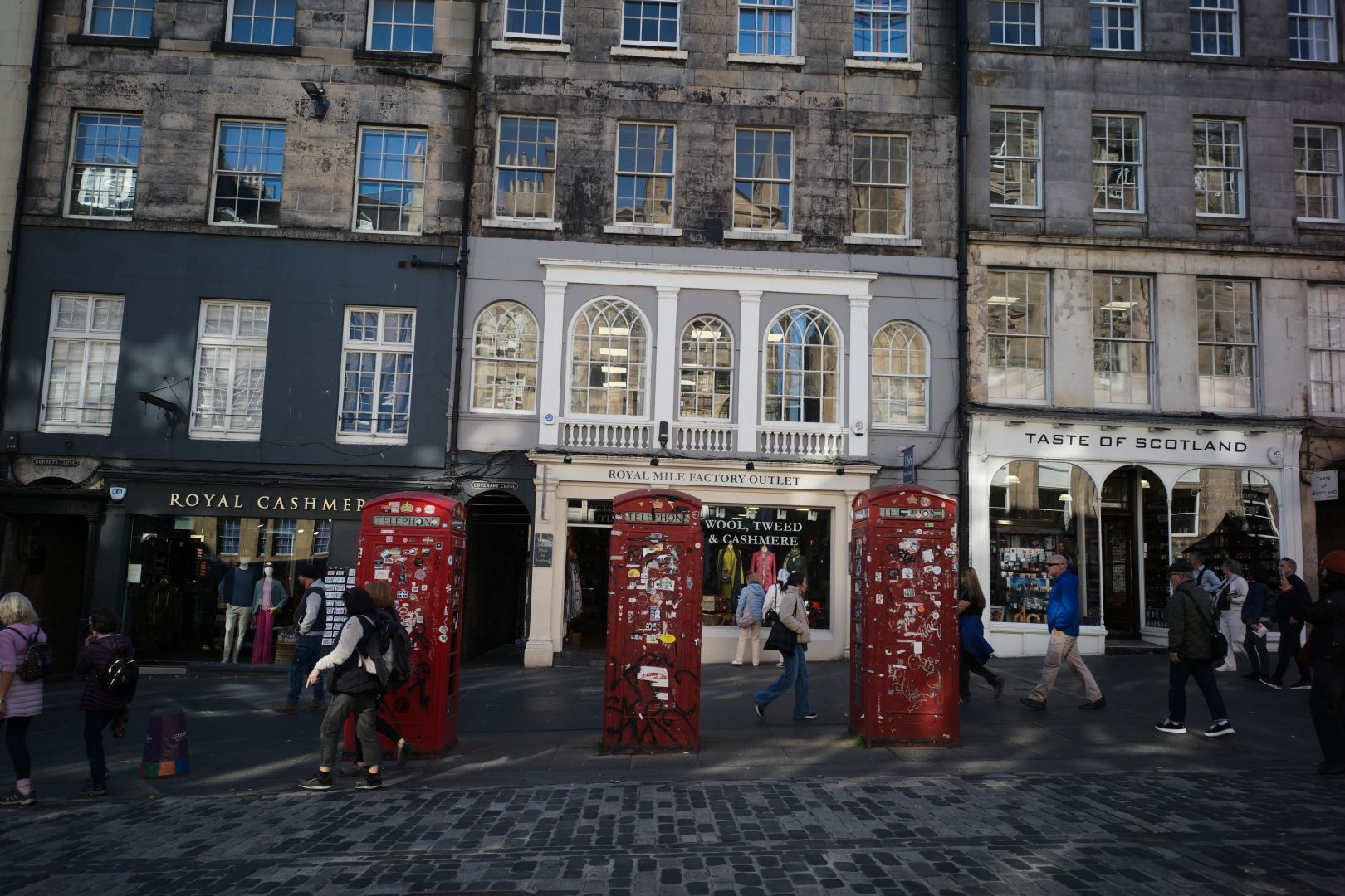 Three red phone boxes lined up along the street of the royal mile
