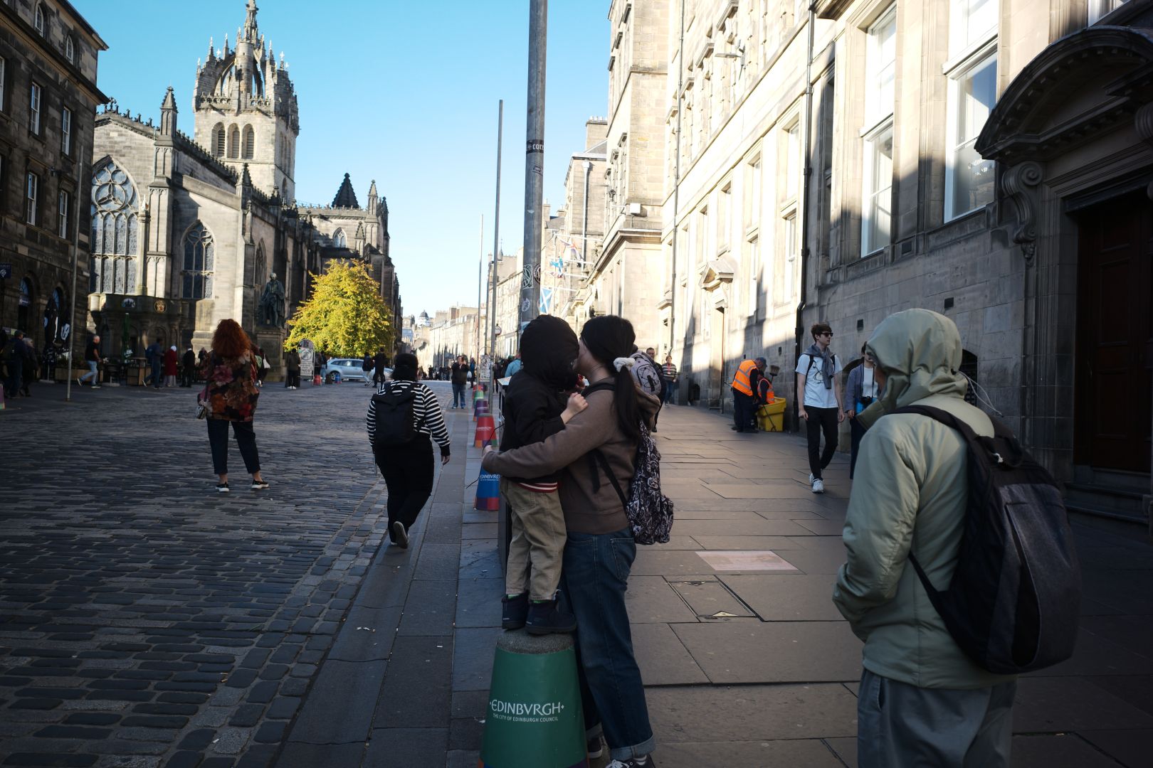 Musuko standing on a bollard, with my sis hugging him, taking in the sights
