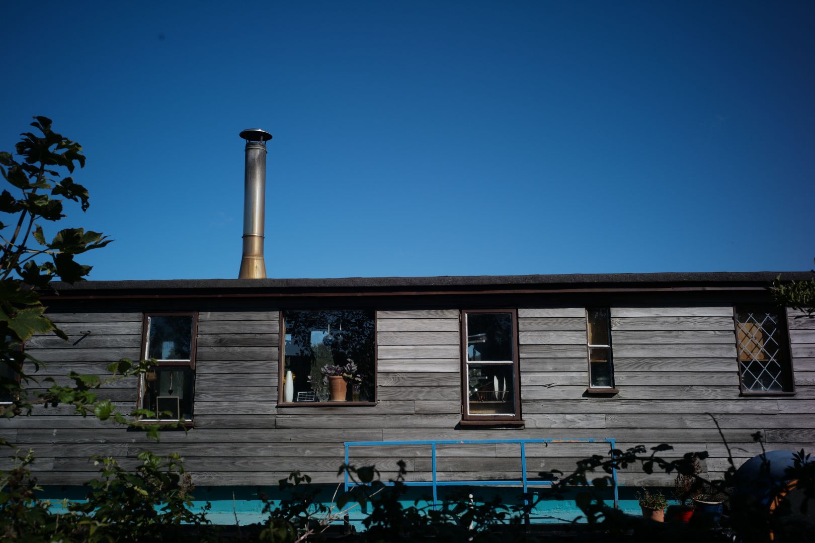 Section of a boathouse wall with windows, underneath a very blue sky